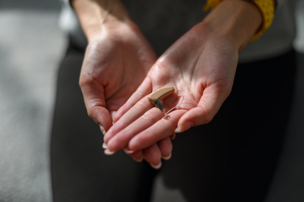 young-woman-hands-holding-a-hearing-aid